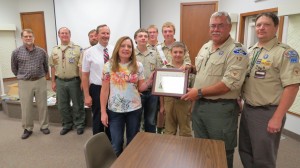 Michelle Rowland, president of the Lime Creek Nature Center Foundation, presents the “Friend of Lime Creek” award to Kent Studer, Scoutmaster of Boy Scout Troop 12 as former scoutmasters and boy scouts look on.