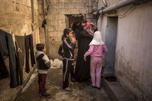 A Syrian mother and her children arrive at the dilapidated basement building where they are staying in Amman, the capital of Jordan. Photo: UNHCR/O. Laban-Mattei