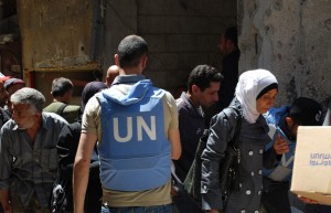 An UNRWA staff member assists Syrians with food aid in Yarmouk, Damascus. Photo: UNRWA Archives