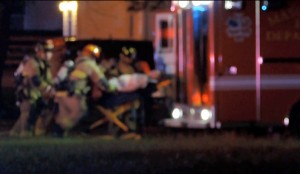 A man from inside the house is rushed into an ambulance.