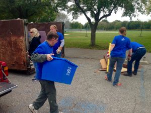 Volunteers load junk and debris into a dumpster